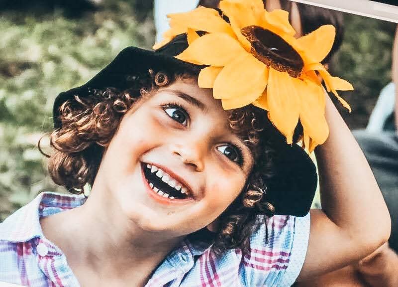 Bambino sorridente con cappello a girasole a uno spettacolo di Ole e Ilvia